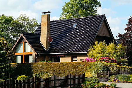 black and brown house covered in plants thumbnail