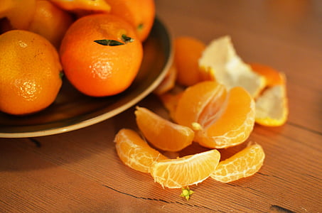 peeled oranges beside oranges on brown plate thumbnail