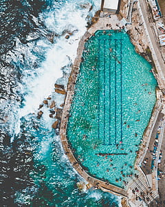 aerial photography of people swimming near pool beside seashore during daytime thumbnail