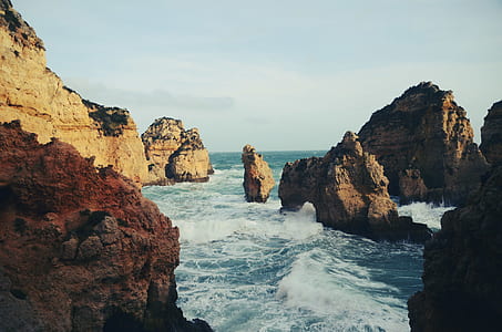 water waves hitting rock formation during daytime thumbnail
