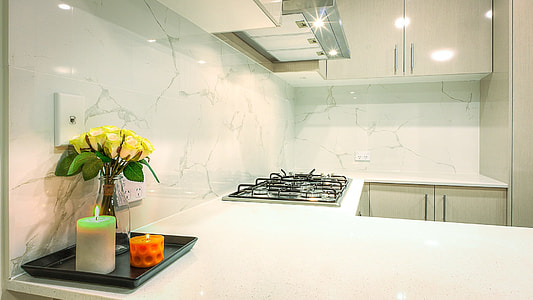 two pillar candles near flower on white marble top kitchen cupboard thumbnail
