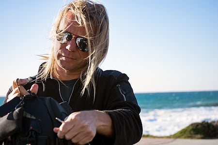 man holding black clothes standing near sea shore thumbnail