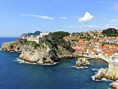 orange-and-white painted houses near blue sea under blue and white sky at daytime thumbnail