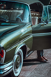 woman in white tank top sitting inside of green Mercedes-Benz car on asphalt road during daytime thumbnail