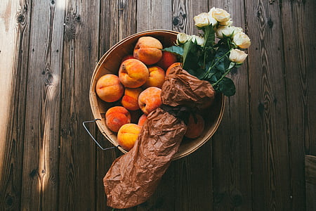 peach fruits in pot and bouquet of white roses placed on brown wooden pallet board thumbnail