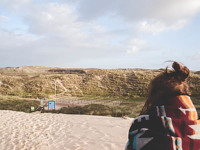 woman in red, black, and white scarf waling on sand thumbnail