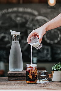 person pouring milk to jar on table thumbnail