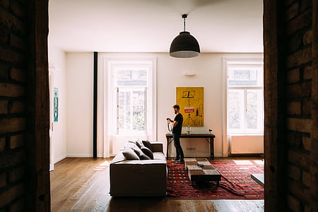 man standing near console table and sofa inside room thumbnail