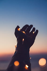 person with outstretched hands having string lights wrapped around it thumbnail