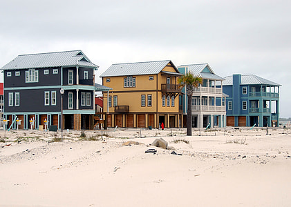 black, brown, and blue painted houses on brown sand under blue sky during daytime thumbnail