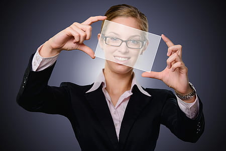 woman wearing black framed eyeglasses and black blazer holding glass panel thumbnail