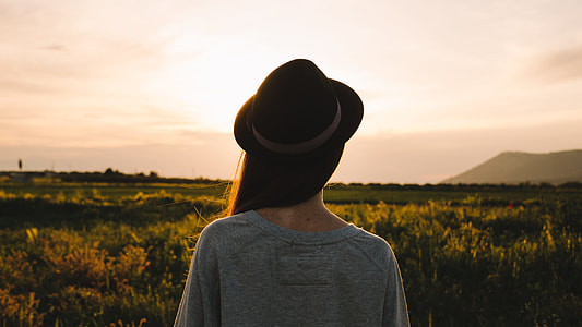 woman in grey shirt and black fedora hat standing during daytime thumbnail