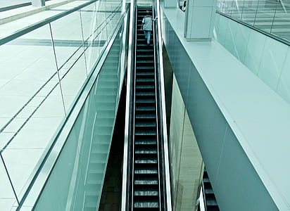 person on escalator inside white painted building thumbnail