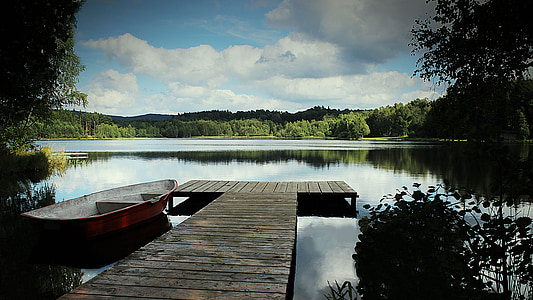 red jon boat beside brown wooden pathway on top of body of water photo thumbnail