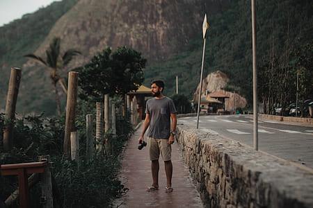 man holding DSLR camera standing on pavement thumbnail