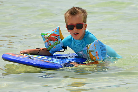 boy holding blue surf board while in water thumbnail
