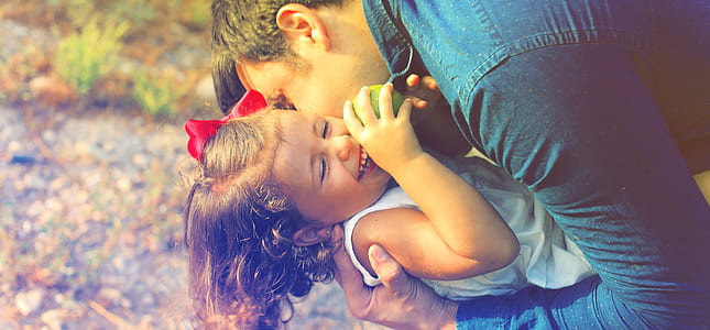 man hugging child while holding apple thumbnail