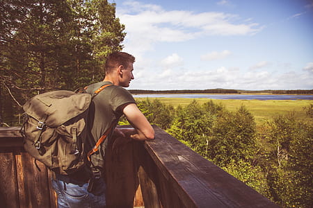 man standing beside brown wooden railing thumbnail