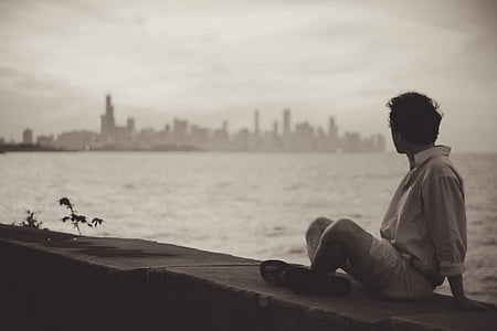 man sitting on bay looking at cityscape thumbnail