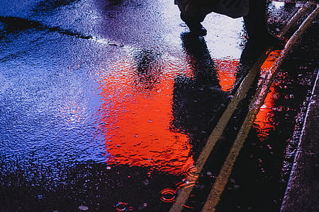 photo of person walking on wet road during nighttime thumbnail