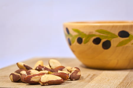 nuts near bowl on wooden surface thumbnail