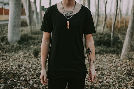 selective focus photography of person wearing black scoop-neck T-shirt standing over dried leaf ground outdoors thumbnail