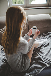 women's grey knit long-sleeve mini dress sitting on grey textile holding ceramic cup thumbnail