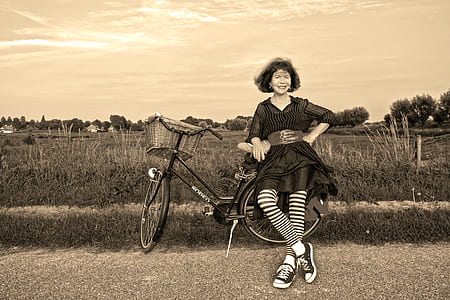 grayscale photography of woman in front of city bicycle thumbnail