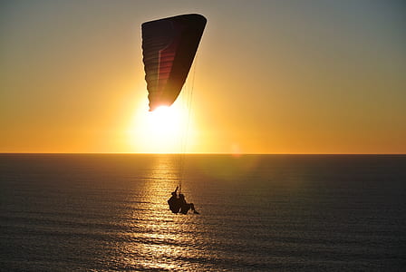 paragliding of two person above water during dusk thumbnail
