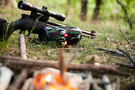 black rifle with scope beside JBL Charge 3 speaker thumbnail