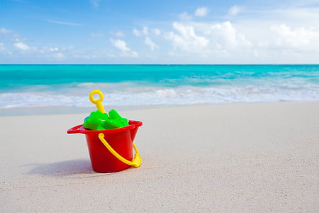 red and yellow plastic pail and shovel near the ocean thumbnail