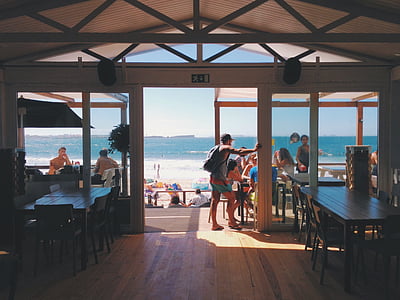 group of people in white and brown wooden house near beach thumbnail
