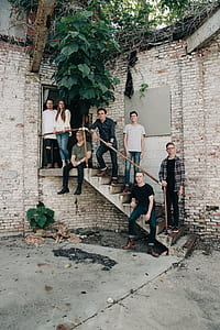 group of men and one woman standing and sitting on stairs thumbnail