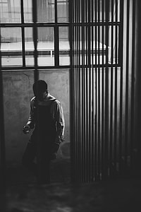 grayscale photo of man wearing overall and long-sleeve shirt walking on stair thumbnail