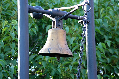brass-colored bell near green leaf plant at daytime thumbnail