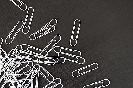 Pile of Silver Paper Clips on Black Desk thumbnail