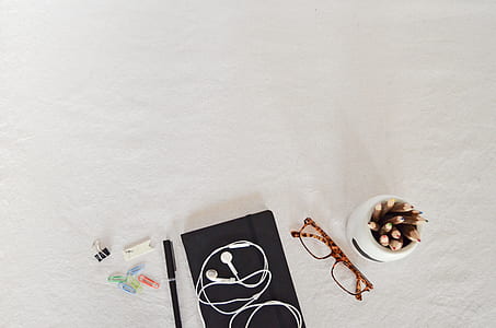 earphones on book beside pen, paper clips, pencil and eyelgasses thumbnail