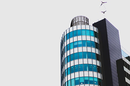 low-angle photography of glass building under gray clouds thumbnail