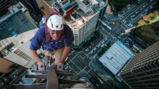 man climbs gray metal frame during daytime thumbnail