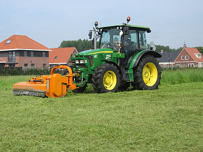 green and yellow tractor cutting grass at daytime thumbnail