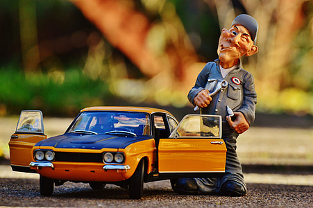 yellow Ford Torino die-cast metal model and male mechanic figurine on ground during daytime thumbnail