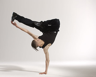 man with black tank top and black pants dancing on white surface close-up photo thumbnail
