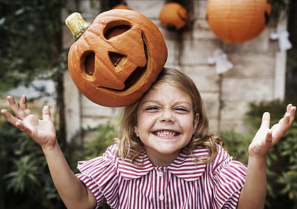 Photo of Girl Smiling With Jack-o'-lantern on Her Head thumbnail
