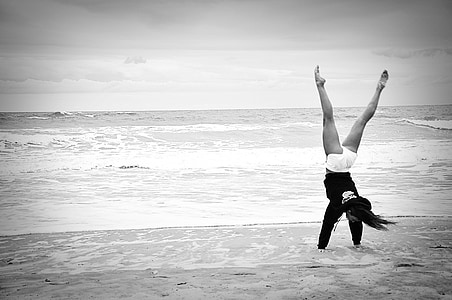 grayscale photo of doing flip on seashore thumbnail