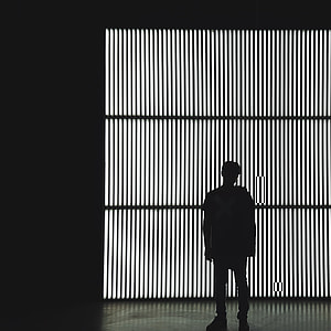 silhouette man in jacket standing in front of light thumbnail