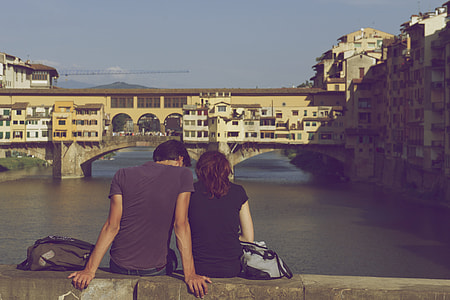man and woman sitting on gray concrete bridge looking to the river at daytime thumbnail