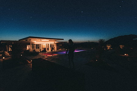 silhouette photo of woman standing at pavement edge under starry night thumbnail