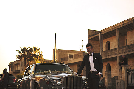 man standing beside silver car thumbnail