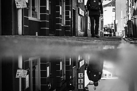 grayscale photography of man walking on street thumbnail