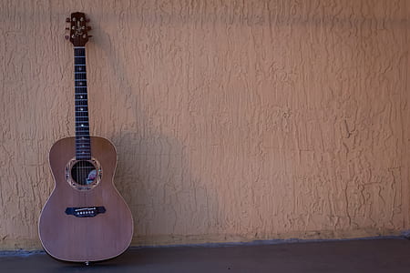 brown acoustic guitar on gray concrete wall thumbnail
